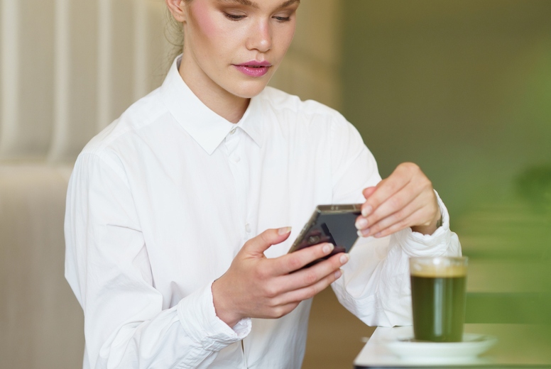 Concentrated businesswoman using phone sitting in a modern cafeteria