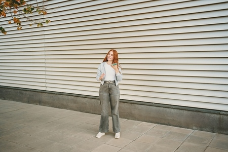 A stylish young woman confidently poses against a backdrop of modern architecture A stylish young woman confidently poses against a backdrop of modern architecture