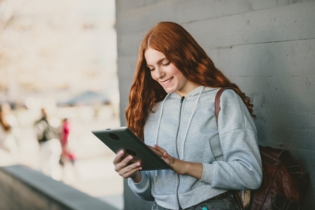 A Young Woman Engaged with Her Tablet in the Outdoors  Enjoying the Surrounding Nature and Life