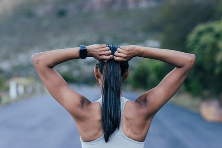 Back view of slim unrecognizable female adjusting her hair while standing outdoors
