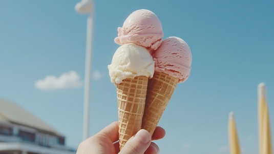 Three ice cream cones held against clear blue sky