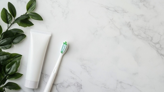 Electric toothbrush and toothpaste tube on marble surface
