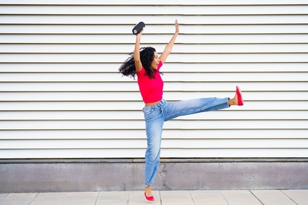 Dynamic and Joyful Dance Pose Captured Against a Striped Background for a Vivid Effect