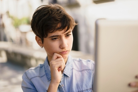 A focused young person works on a laptop outdoors  enjoying nature and their surroundings