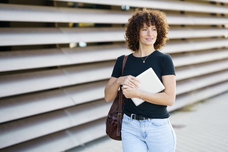 A young woman with a laptop in a vibrant city reflects her active lifestyle and career goals A young woman with a laptop in a vibrant city reflects her active lifestyle and career goals