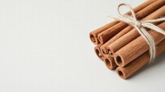 Bundle of cinnamon sticks tied with twine on white background