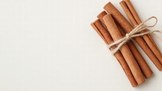 Bundle of cinnamon sticks tied with twine on light background