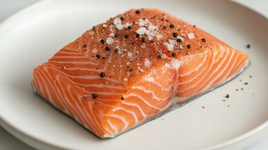 Fresh salmon fillet with salt and pepper on white plate