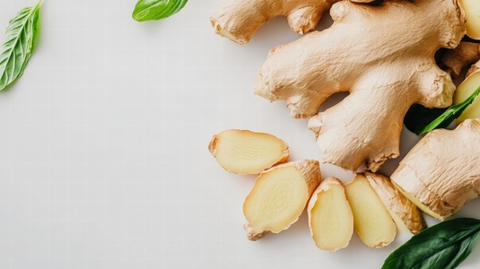 Fresh ginger root with slices and basil leaves on white background