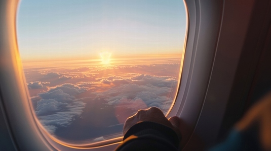 person gazes out airplane window at stunning sunset over clouds