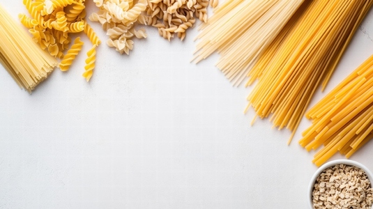 Various dried pasta types neatly arranged on white surface