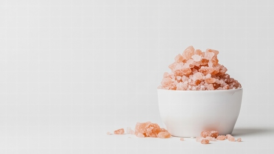 Small bowl of pink Himalayan salt with scattered crystals Small bowl of pink Himalayan salt with scattered crystals