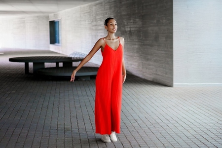 A Stylish Woman Dressed in a Vibrant Red Jumpsuit Posing Confidently Amidst Modern Architecture