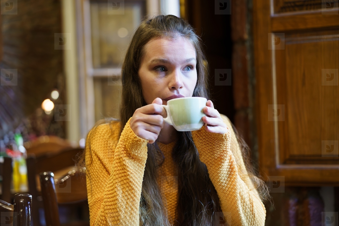 Young Woman Enjoying a Warm Beverage in a Cozy Caf