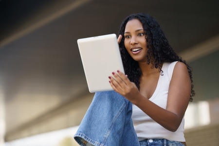 A young woman happily engaged with her tablet while enjoying the outdoors in nature