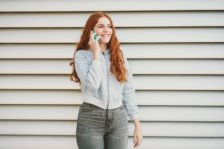 A Cheerful Young Woman Engaged in a Phone Conversation Set Against a Contemporary Background A Cheerful Young Woman Engaged in a Phone Conversation Set Against a Contemporary Background