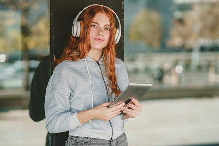 A Young Woman Wearing Headphones Enjoying Music While Using a Tablet Device to Relax