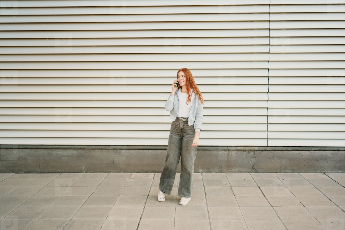 A casual young woman  dressed in a trendy and stylish outfit  is engaging in a phone conversation