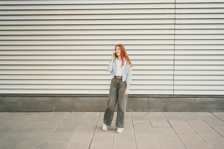 A casual young woman  dressed in a trendy and stylish outfit  is engaging in a phone conversation