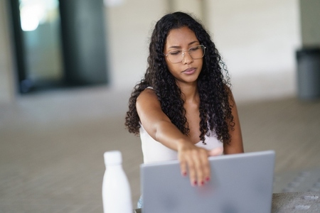 A Young Woman is Actively Engaged in Work on Her Laptop While in a Modern Workspace Environment