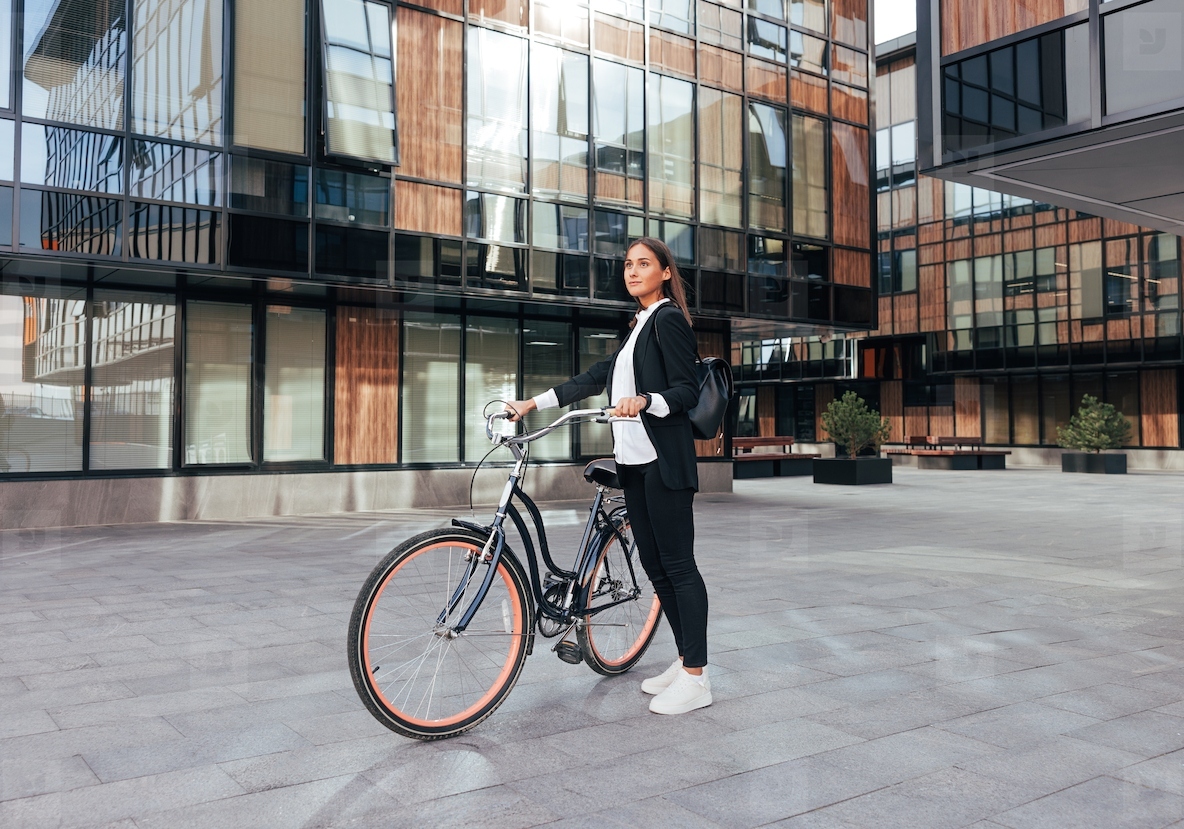 Full length of a young woman entrepreneur standing with a bicycle in the city Female in formal wear going to work by bicycle