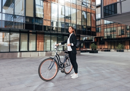 Full length of a young woman entrepreneur standing with a bicycle in the city  Female in formal wear going to work by bicycle