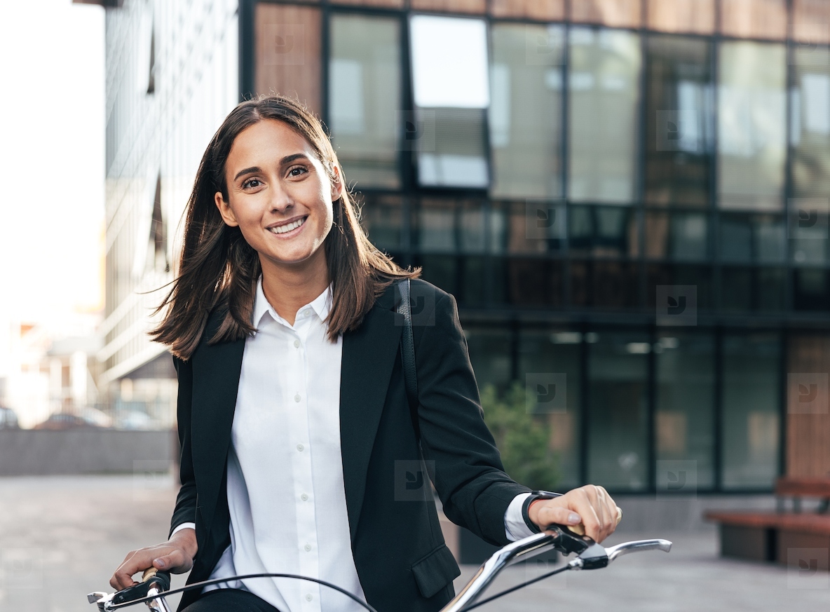 Portrait of young female with a bicycle and formal wear standing in the city and looking at camera