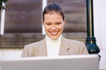 A Smiling Businesswoman is Engaged with Her Laptop While Outdoors  Enjoying the Day