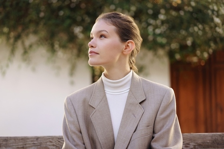 Contemplative Woman in a Stylish Blazer Enjoying Time Outdoors Surrounded by Nature and Greenery
