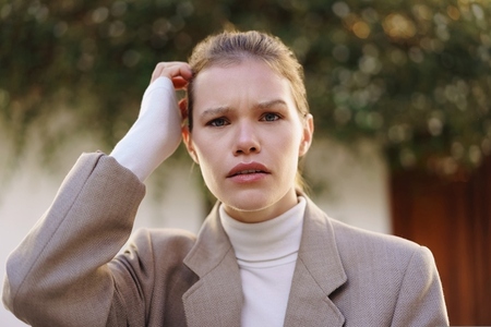 A woman in professional attire with a bandaged hand reflects on lifes many challenges