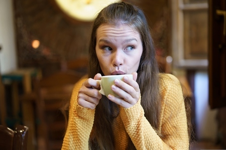 Contemplative Young Woman Enjoying Coffee in Caf