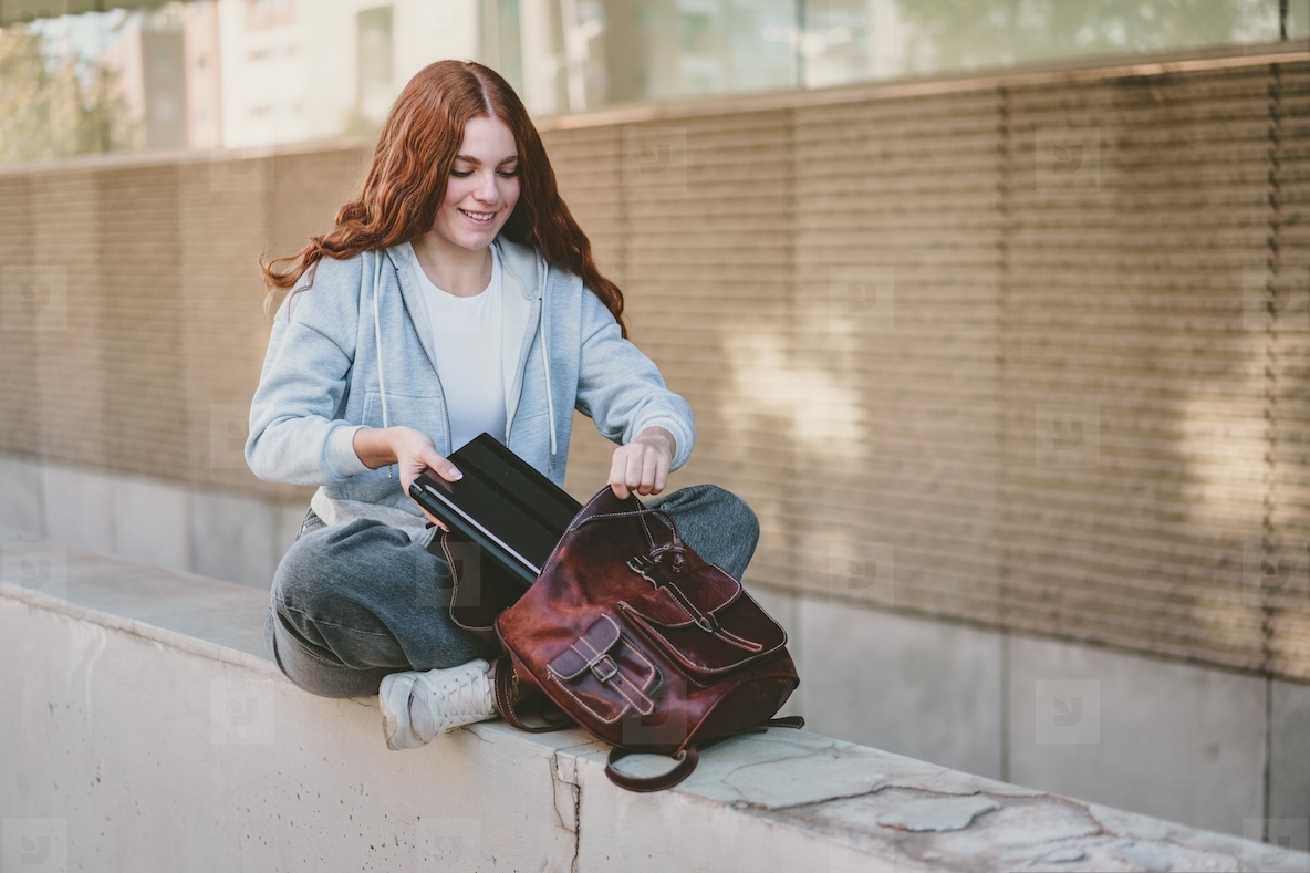A Young Woman is Actively Organizing Her Backpack While Enjoying a Beautiful Outdoor Setting
