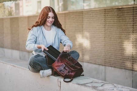 A Young Woman is Actively Organizing Her Backpack While Enjoying a Beautiful Outdoor Setting