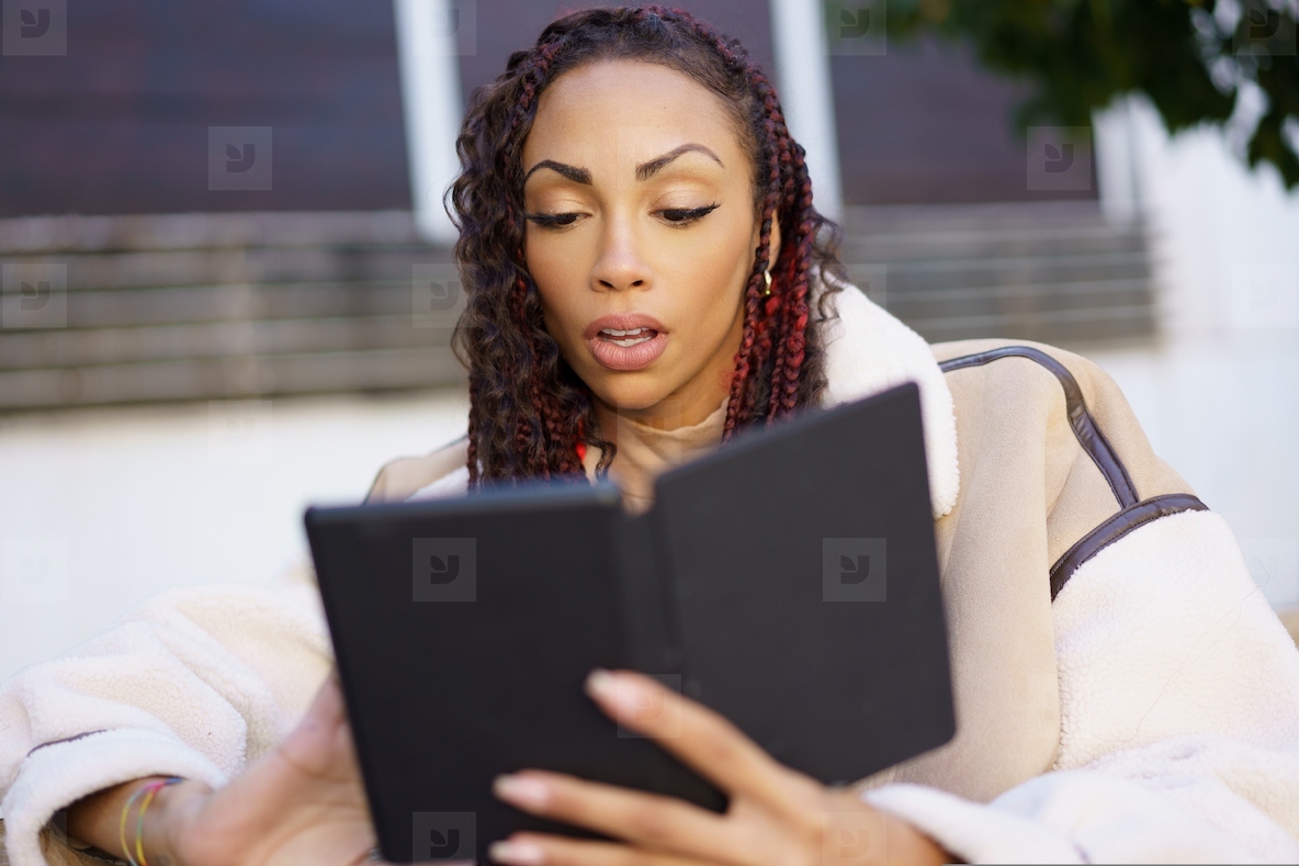 An Engaged Reader Is Enjoying Their Digital Book While Relaxing Outdoors in Natures Beauty