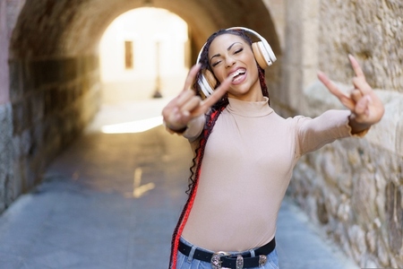 A Joyful Young Woman in Headphones Who is Expressing Freedom in a Bustling Urban Setting
