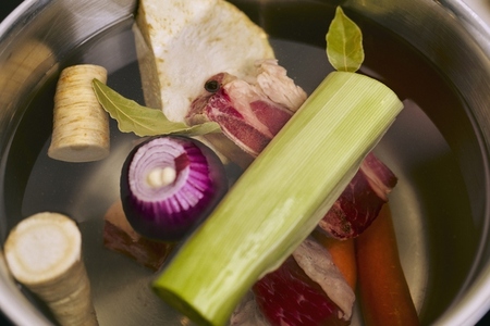 Still life raw vegetables and meat ingredients floating in soup pot