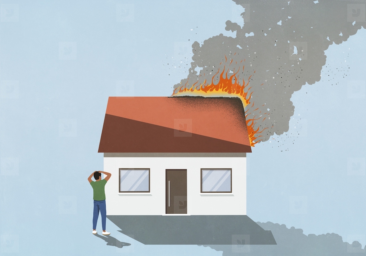 Man with head in hands watching burning house