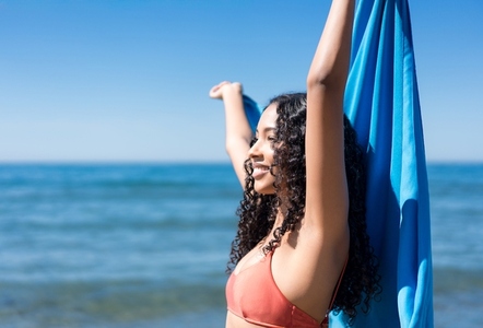 A Joyful Woman Happily Enjoying Her Day at the Beach While Wearing a Beautiful Colorful Scarf