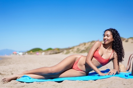 A Relaxing Beach Day A Sunbathing Woman Enjoying the Comfort of the Sandy Shoreline