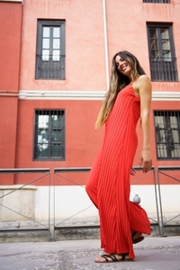 An Elegant Woman in a Stunning Red Dress Posing Beautifully Against a Vibrant Urban Backdrop