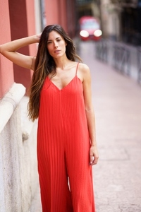 A Stylish Woman Dressed in a Bold Red Jumpsuit Posing Confidently on an Urban Street Scene A Stylish Woman Dressed in a Bold Red Jumpsuit Posing Confidently on an Urban Street Scene