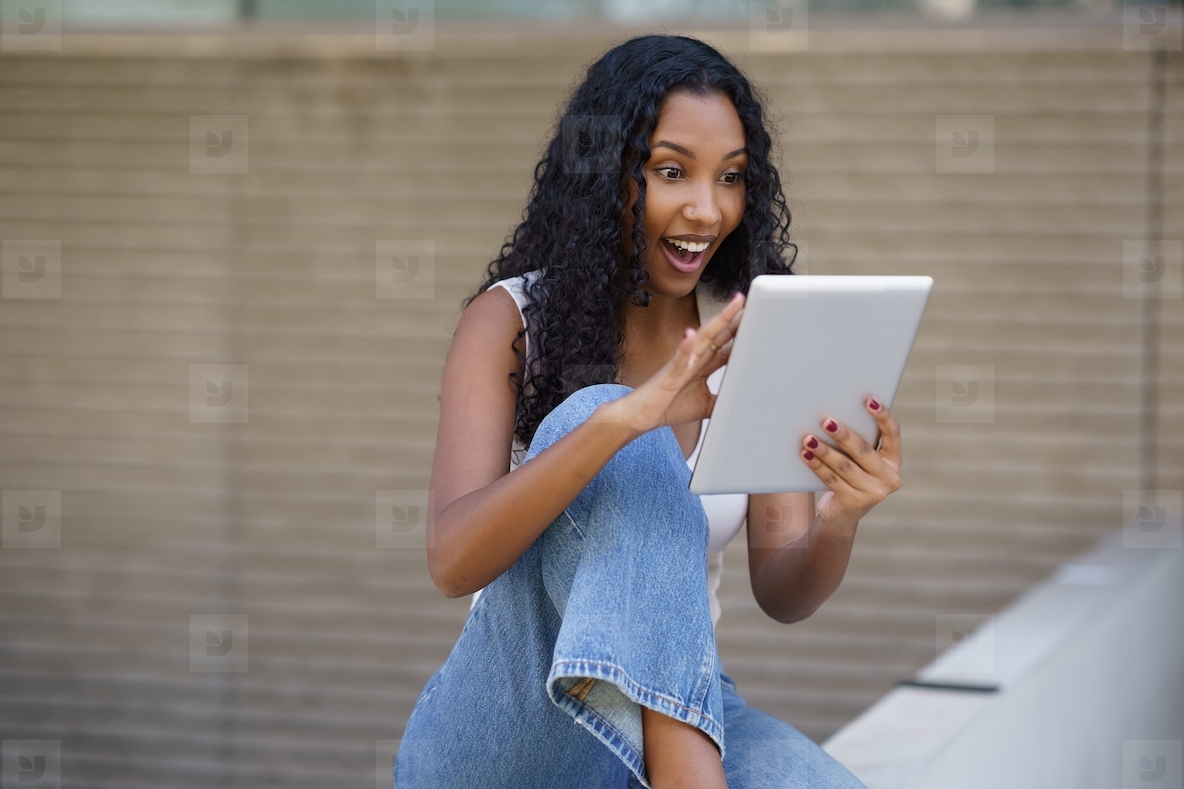 An Excited Young Woman Engaging with a Tablet and Displaying a Joyful Expression on Her Face