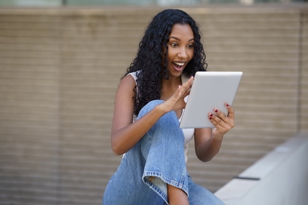 An Excited Young Woman Engaging with a Tablet and Displaying a Joyful Expression on Her Face