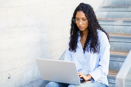 A Focused Young Woman Engaged in Serious Work on Her Laptop in a Chic Modern Interior Setting