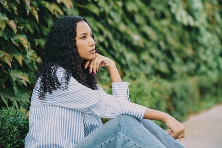 A Thoughtful Woman Lost in Nature  Sporting Beautiful Curly Hair  Dressed in Casual Attire