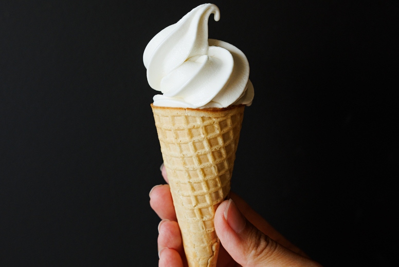 Hand of an unrecognizable person holding an ice cream cone over a black background