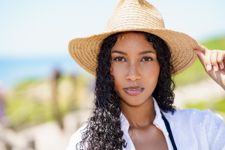 A Beautiful Sunlit Portrait of a Young Woman Wearing a Stylish Straw Hat at the Beach A Beautiful Sunlit Portrait of a Young Woman Wearing a Stylish Straw Hat at the Beach