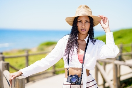 A Stylish Woman Enjoying a Day at the Beach with a Camera and a Beautiful Sun Hat