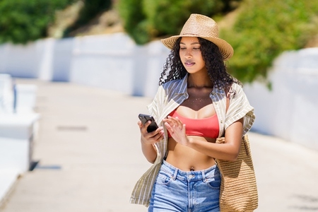 A Stylish Woman in a Chic Summer Outfit is Enjoying a Relaxing Day Outdoors with Her Smartphone