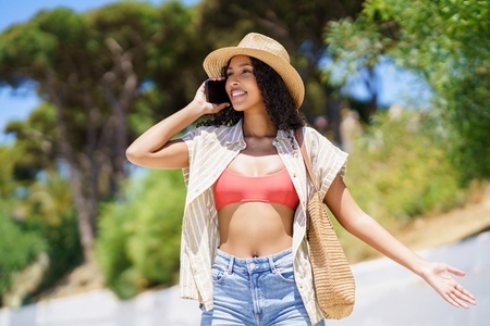 A young woman joyfully enjoys a summer day in a casual outfit and stylish straw hat